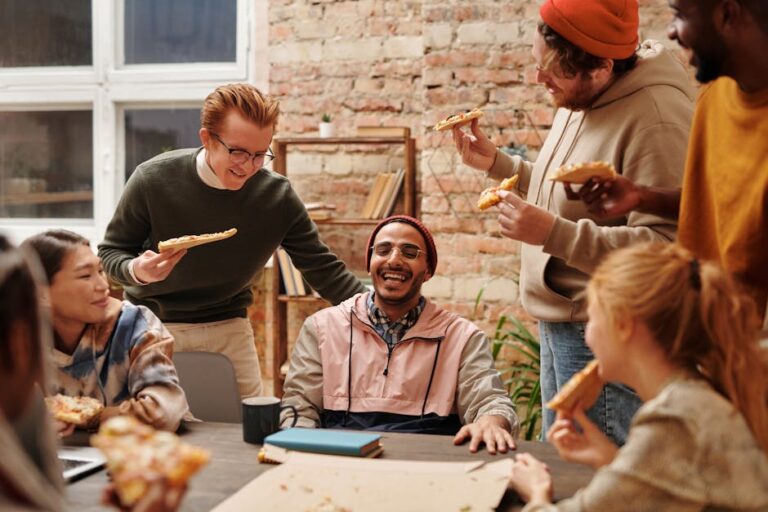 A joyful group of diverse friends enjoying pizza together in a cozy indoor setting.